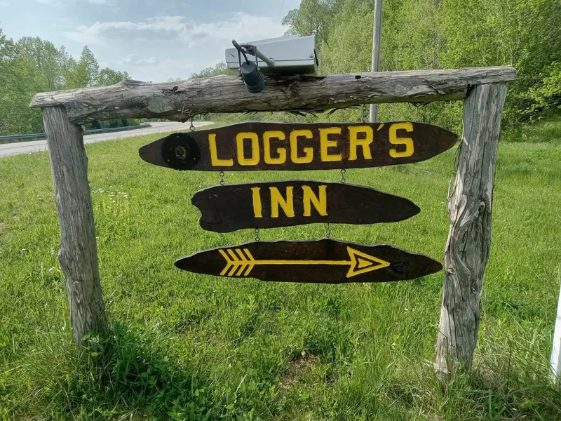 Logger's Inn wooden entrance sign by the road on Fly Rd